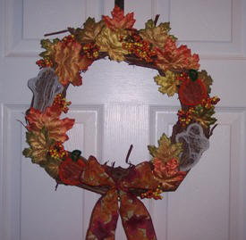 closeup view of our grapevine wreath filled with fall leaves, pumpkins & ghosts